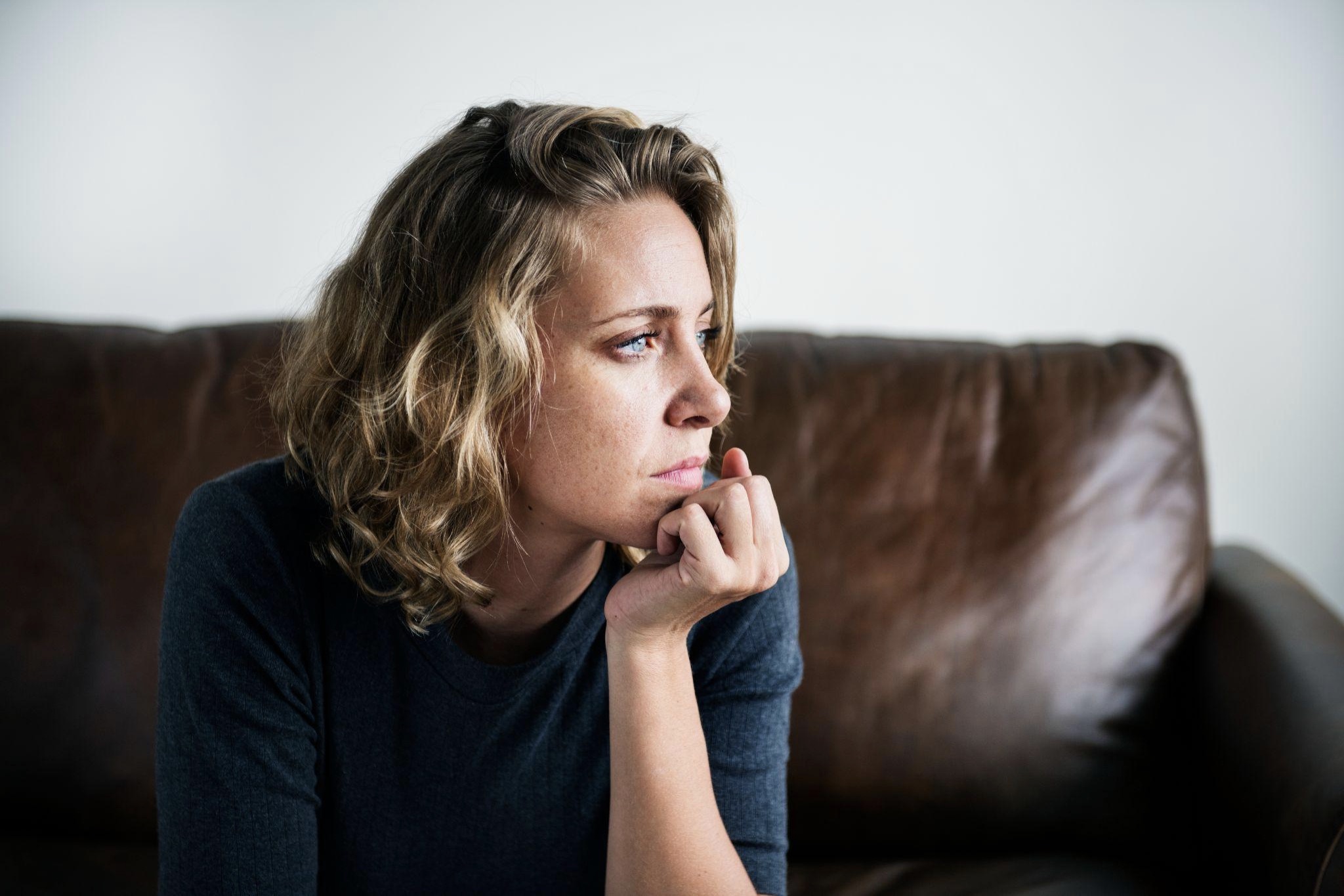 Woman with Blue Eyes Sitting on Couch Looking out Window Image via Rawpixel