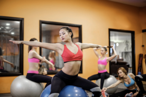 Asian Woman on Exercise Ball in fitness studio guest post Stephanie Haywood 3.30.22