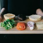 woman holding cutting board with burger and fixings emy 90710FOygrg unsplash copy