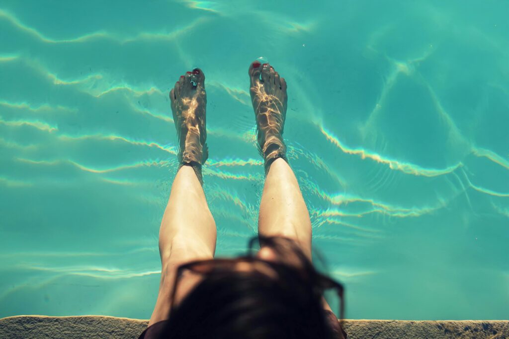 person with their feet in swimming pool water pexels work2survive 31523116 copy