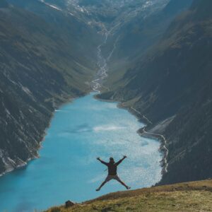 person jumping in mountains over resevoirpaul pastourmatzis 8kDOOrs608I unsplash