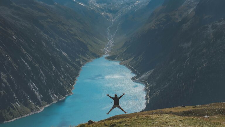 person jumping in mountains over resevoirpaul pastourmatzis 8kDOOrs608I unsplash